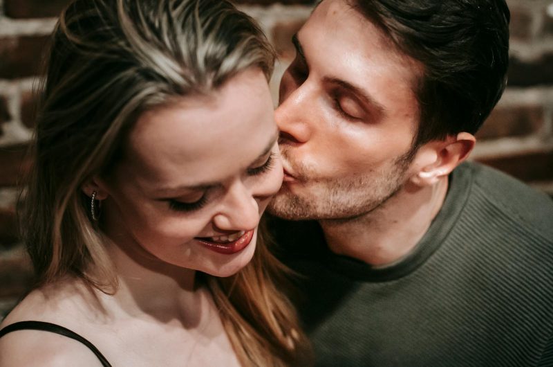 Happy young man kissing girlfriend in room